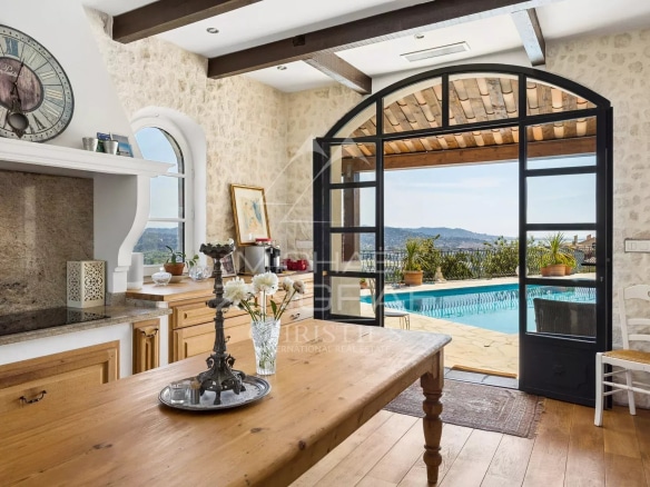 Intérieur d'une maison de charme avec vue sur la mer, cuisine en pierre et accès à une terrasse.
