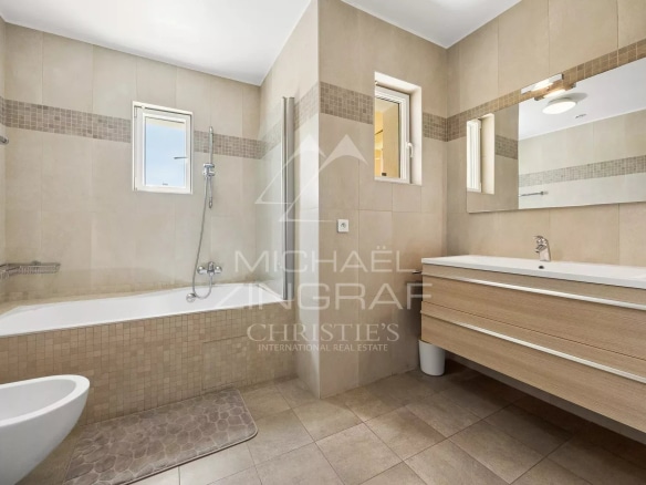 Modern bathroom with bathtub, shower and wooden vanity unit.