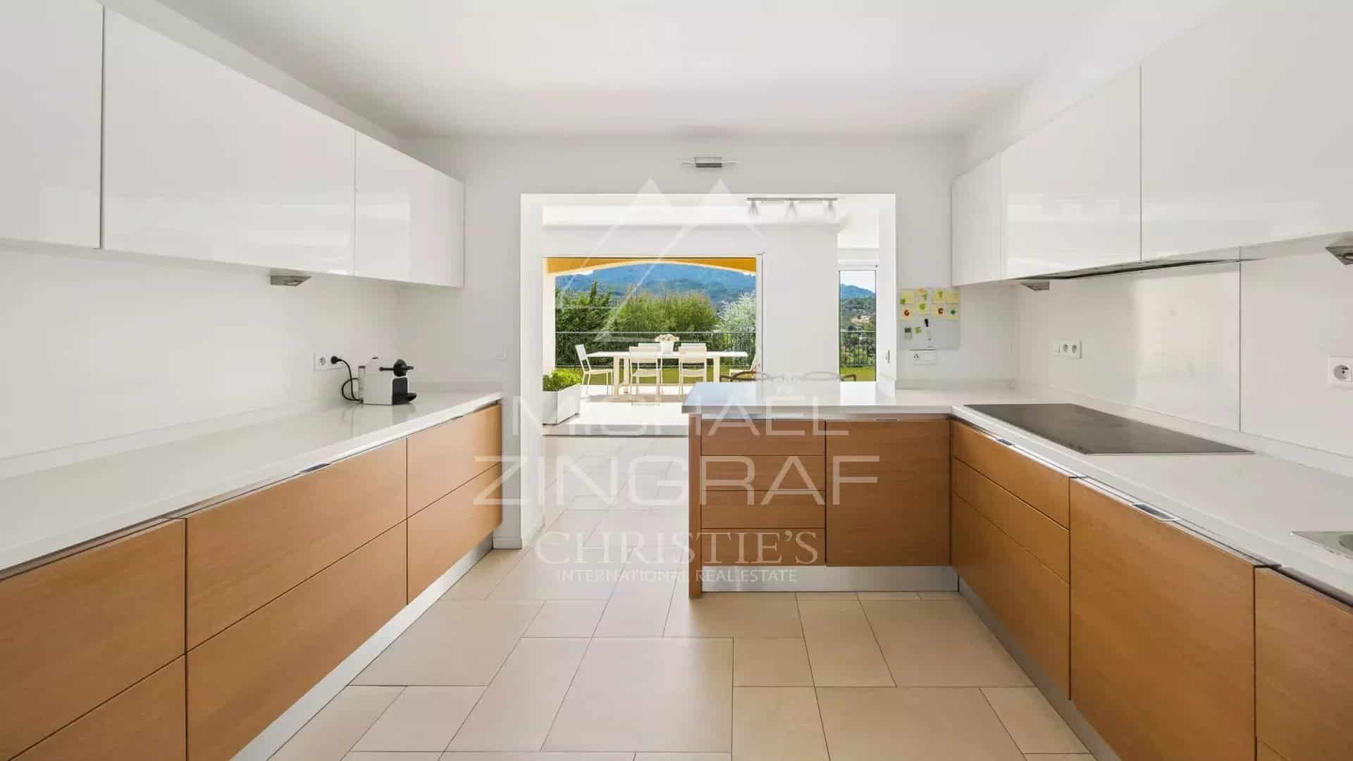 Contemporary cuisine in Mandelieu-la-Napoule Modern kitchen with wood and white furniture, overlooking the terrace and garden.