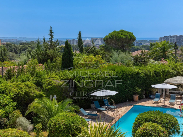Vue d'une villa Belle Époque avec piscine et jardin à Mandelieu-la-Napoule, mer en arrière-plan.