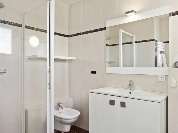 Salle de bain moderne avec douche, lavabo et toilettes.