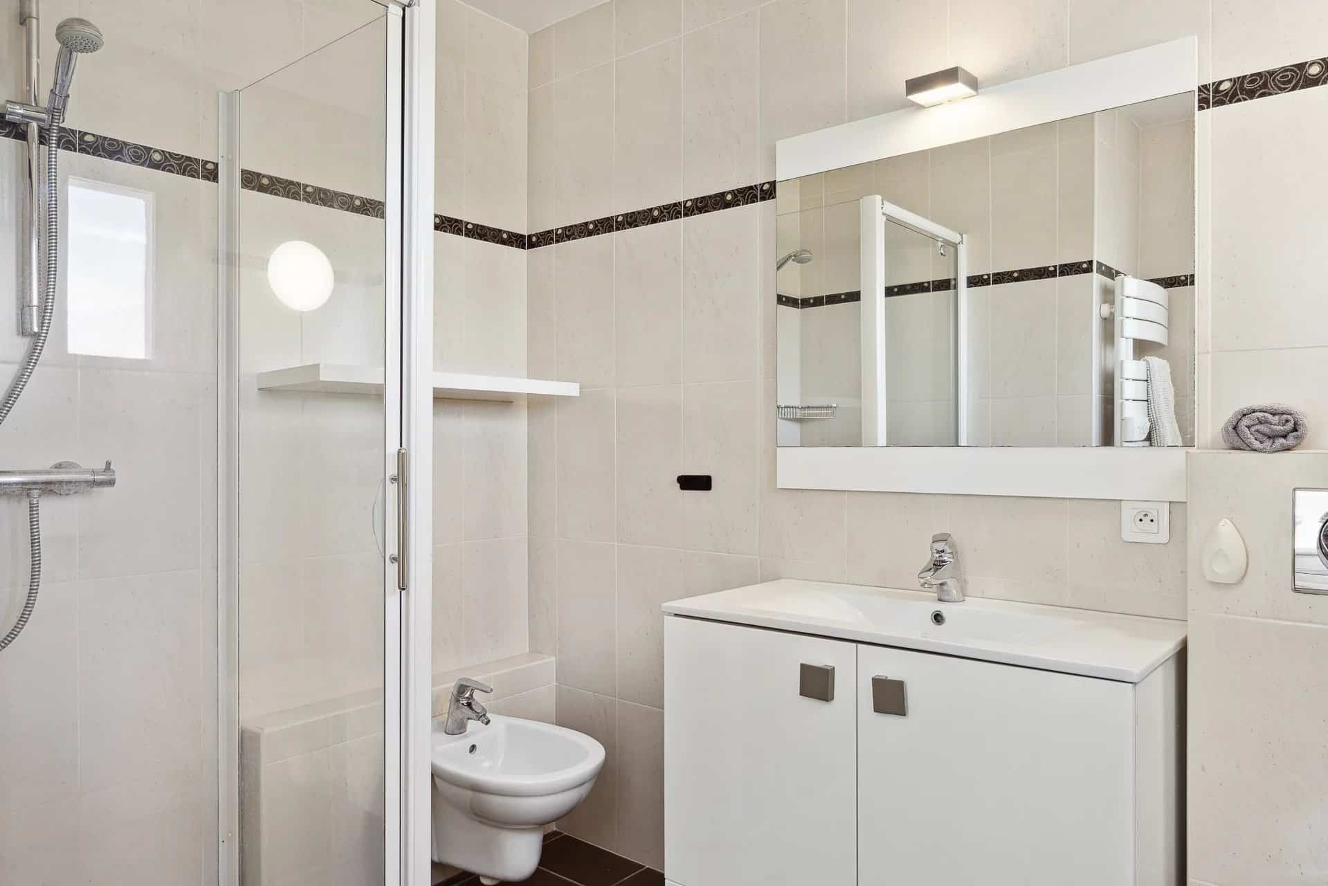 Salle de bain moderne avec douche, lavabo et toilettes.