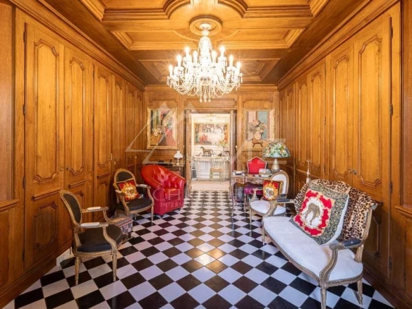 Intérieur d'une villa Art Déco avec un sol en damier noir et blanc et des murs en bois, éclairé par un lustre.