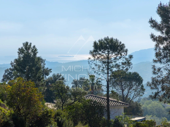 Terrain plat avec vue sur le massif de l'Estérel et la baie de Cannes, entouré de végétation.