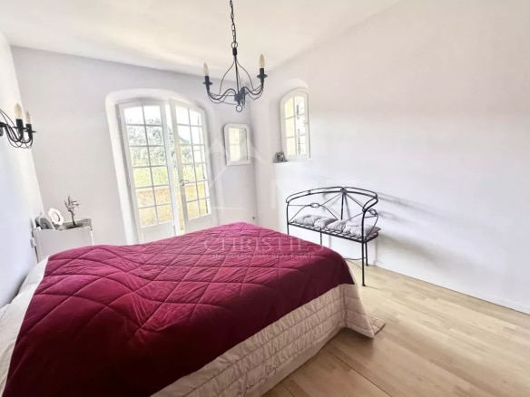 Chambre d'une maison à Mandelieu-la-Napoule avec lit et fenêtres donnant sur l'extérieur.
