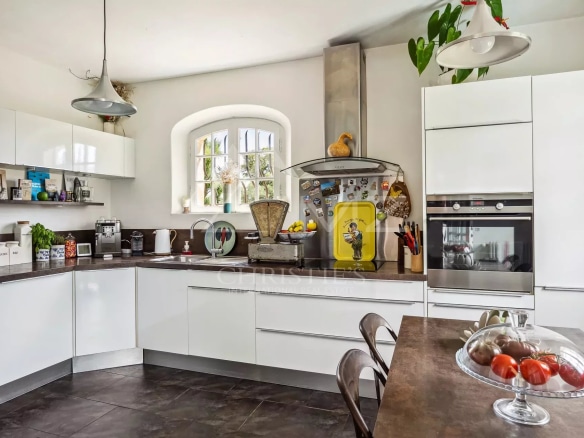 Cuisine moderne et lumineuse avec meubles blancs et plan de travail en noir.