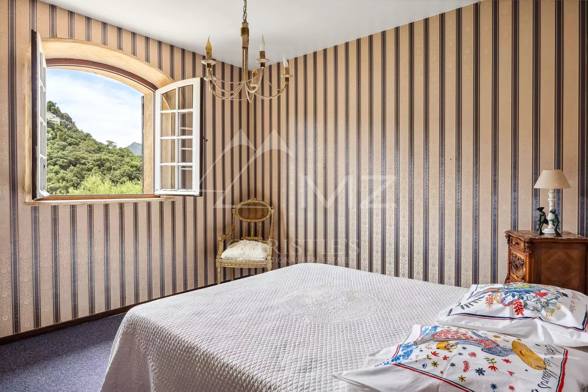 Chambre avec fenêtre et décoration à rayures, vue sur la nature à Mandelieu-la-Napoule.