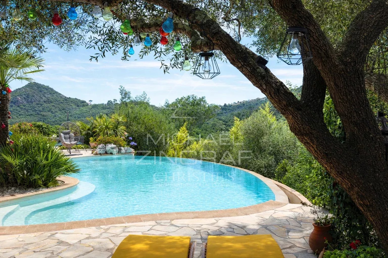Vue d'une piscine entourée de verdure et de collines à Mandelieu-la-Napoule.