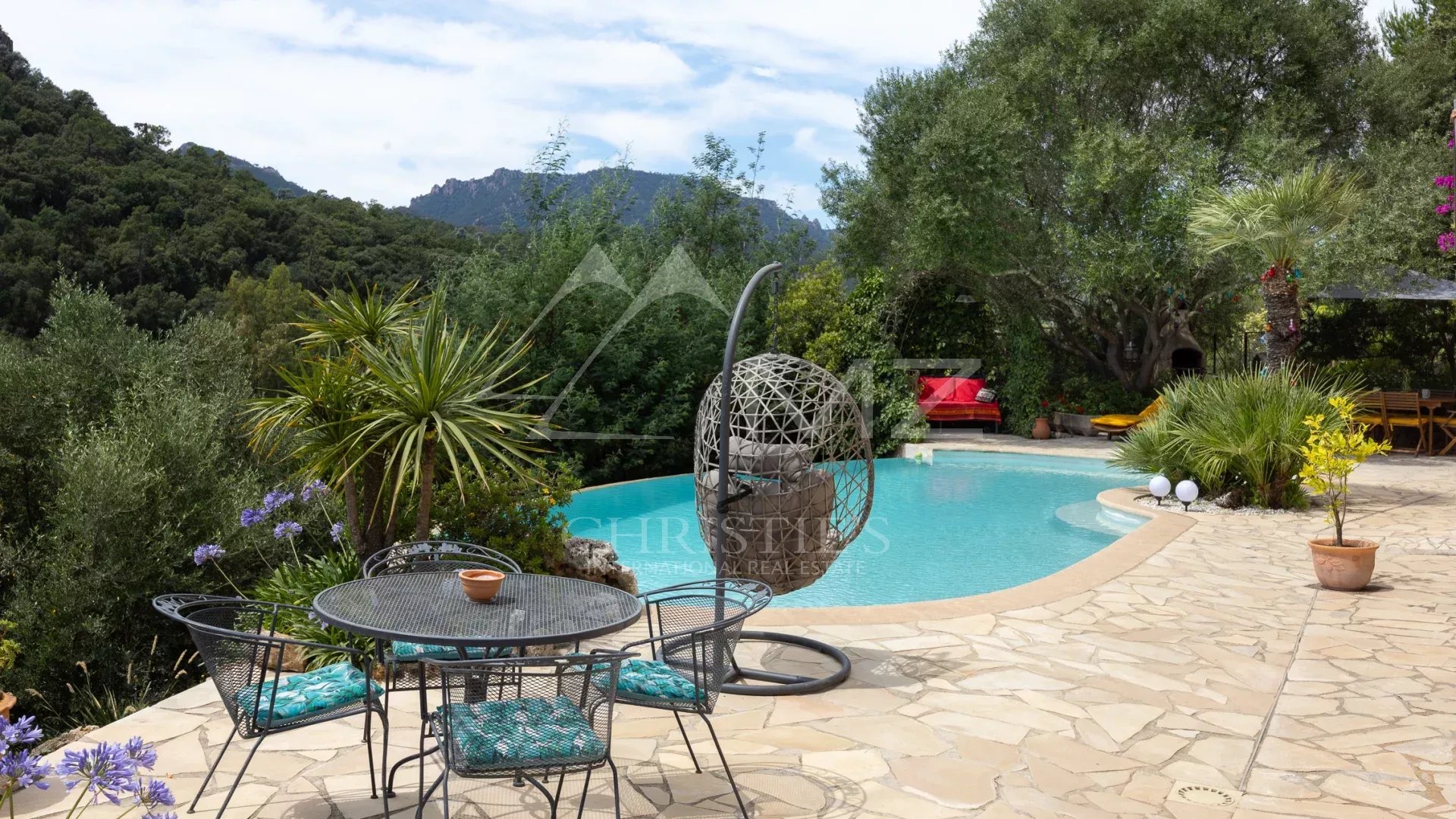 Terrasse avec piscine et mobilier extérieur dans un jardin verdoyant