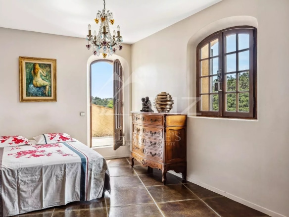 Chambre d'une maison à Mandelieu-la-Napoule avec lit, meuble en bois et fenêtre donnant sur l'extérieur.