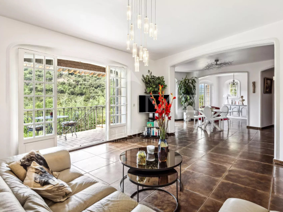 Intérieur d'une maison avec salon lumineux et salle à manger, vue sur les collines.
