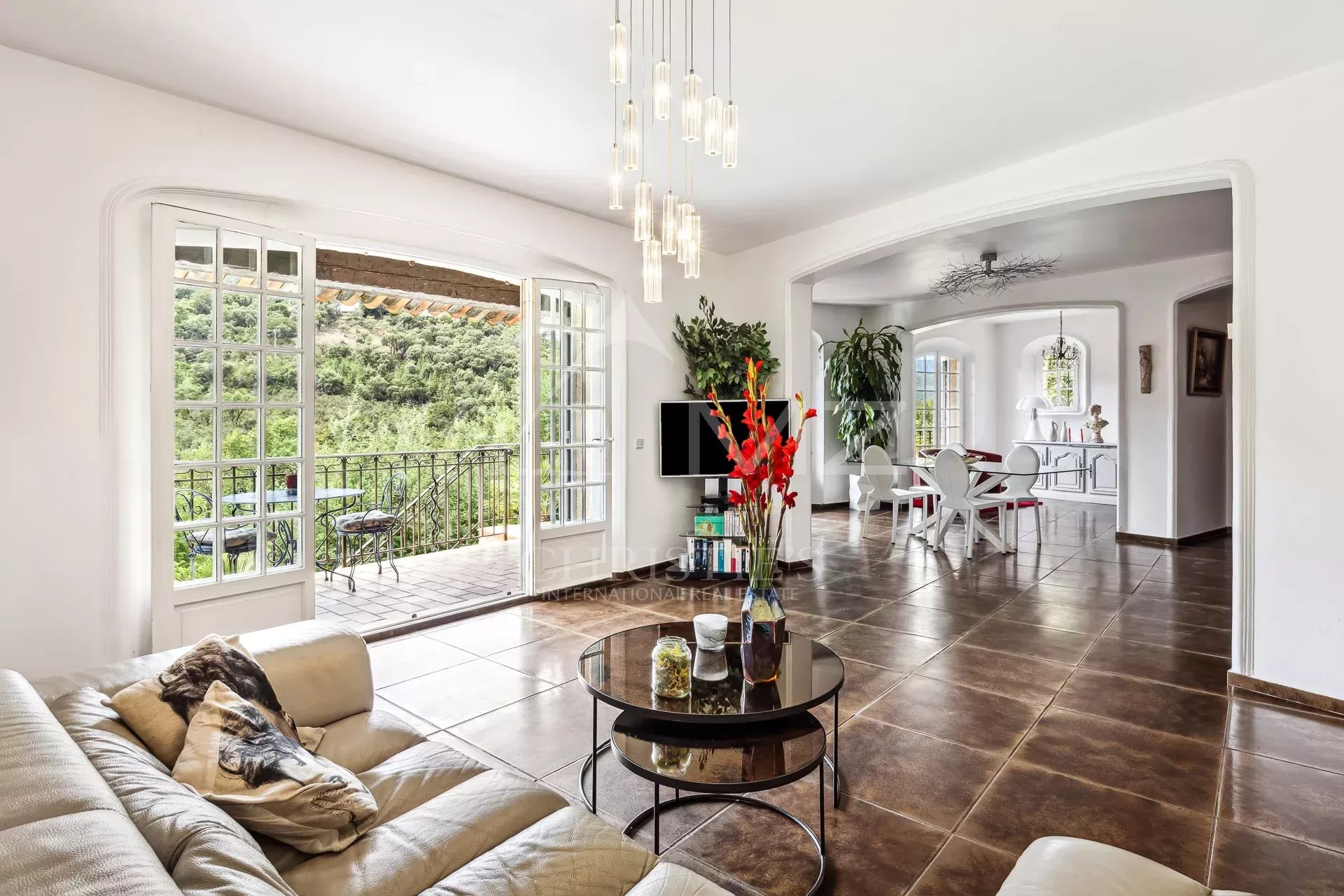 Intérieur d'une maison avec salon lumineux et salle à manger, vue sur les collines.