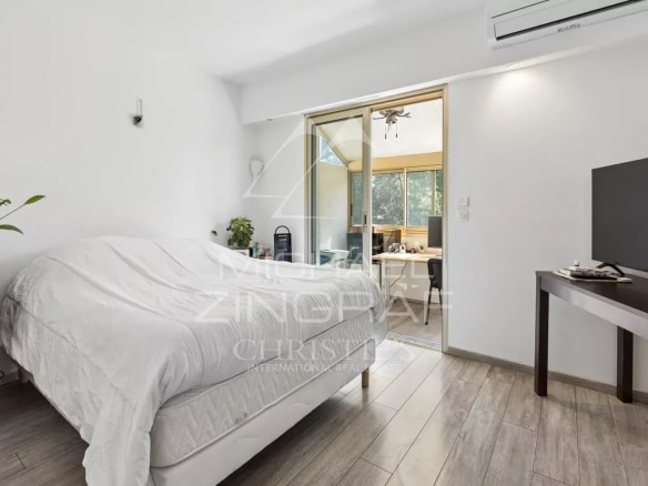 Chambre d'un appartement avec lit, télévision et accès à un balcon.