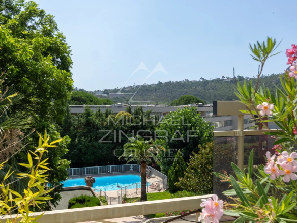 Vue depuis une terrasse d'appartement avec piscine et verdure à Mandelieu-la-Napoule.