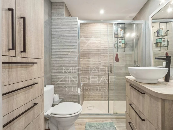 Salle de bain moderne avec douche, lavabo et toilettes dans un appartement.