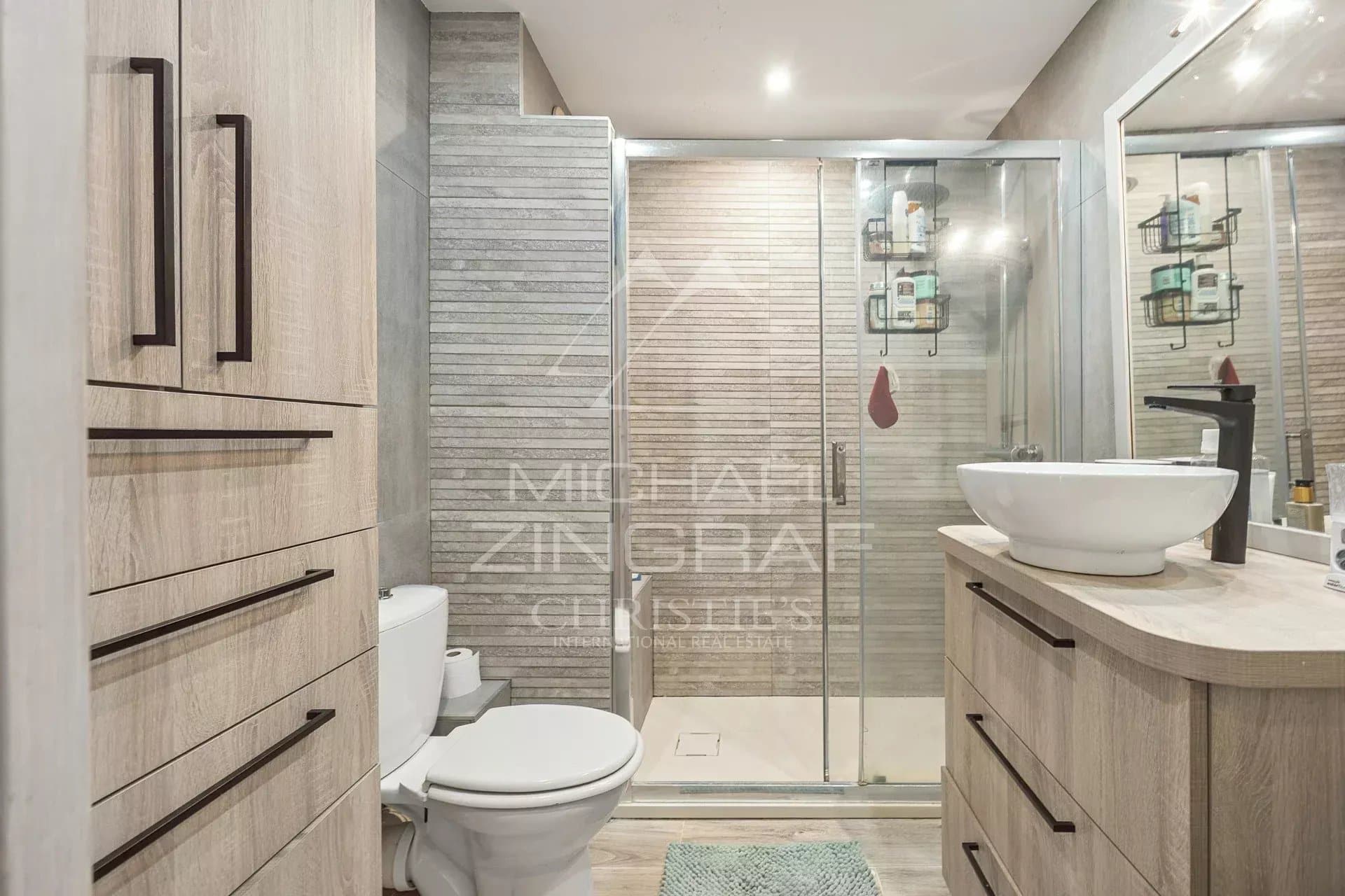 Salle de bain moderne avec douche, lavabo et toilettes dans un appartement.