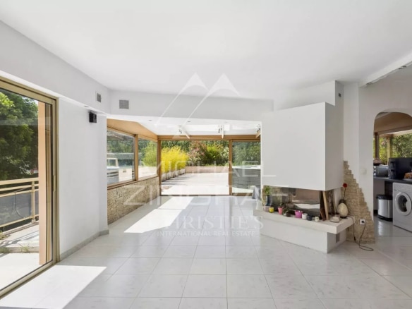 Intérieur d'un appartement lumineux avec séjour spacieux et cuisine ouverte, fenêtres sur terrasse.