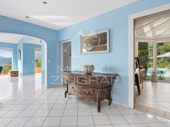 Interior of a bright villa with blue walls and white tiles, overlooking nature.