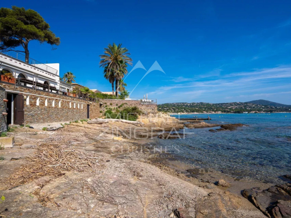 Vue de la villa en bord de mer à Sainte-Maxime, avec des rochers et la mer en arrière-plan.