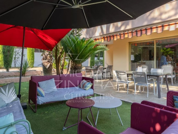 Espace extérieur d'une propriété à Mandelieu-la-Napoule avec salon de jardin et parasol.