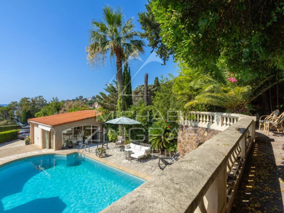 Villa with swimming pool and sea view in Théoule-sur-Mer, surrounded by greenery.