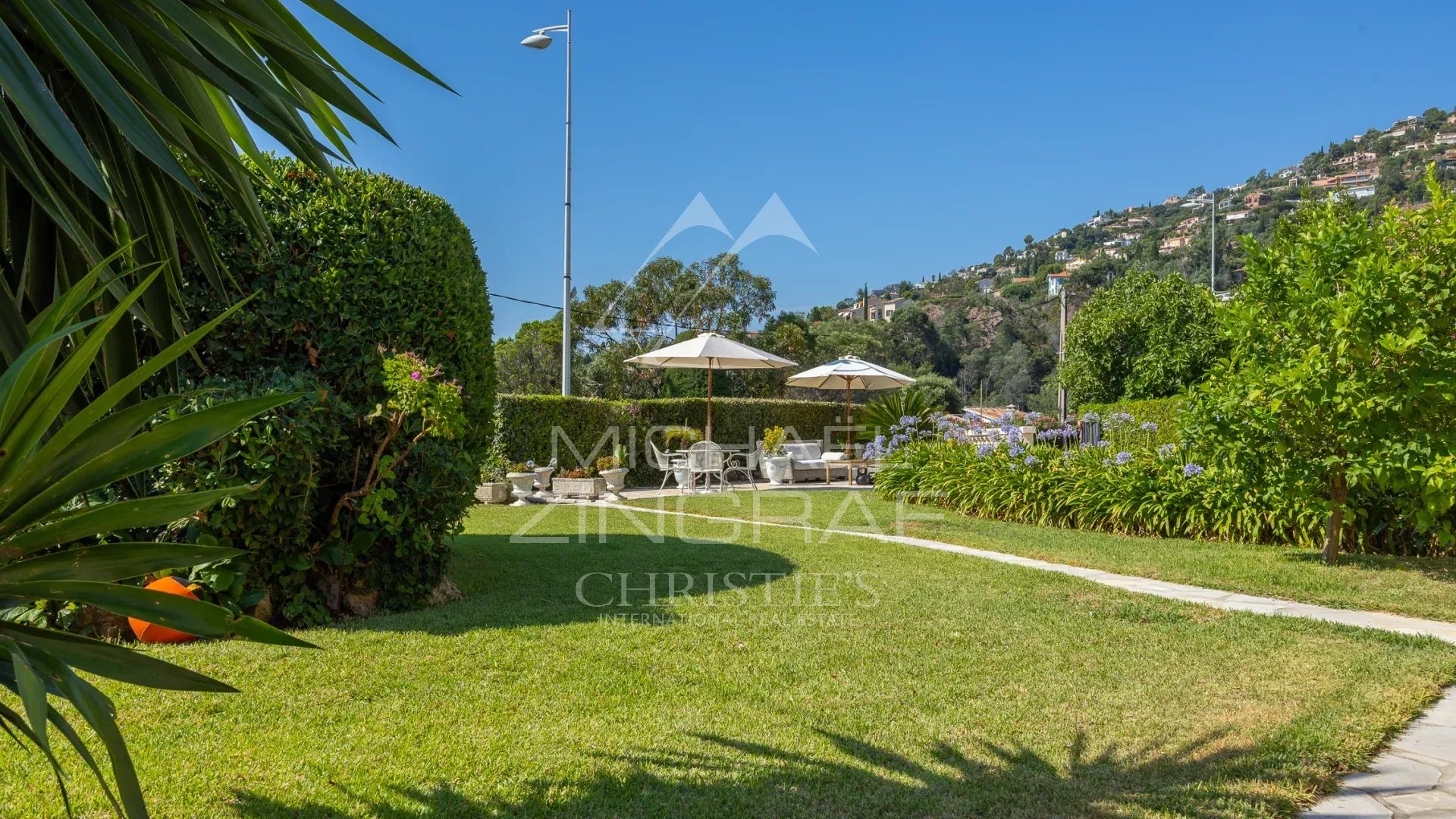 Villa garden in Théoule-sur-Mer Landscaped garden with parasols and views of the hills in Théoule-sur-Mer
