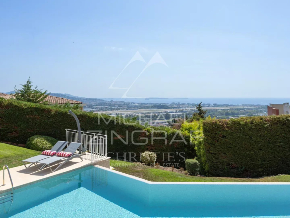 Vue d'une villa avec piscine et jardin, offrant une vue panoramique sur la mer à Mandelieu-la-Napoule.