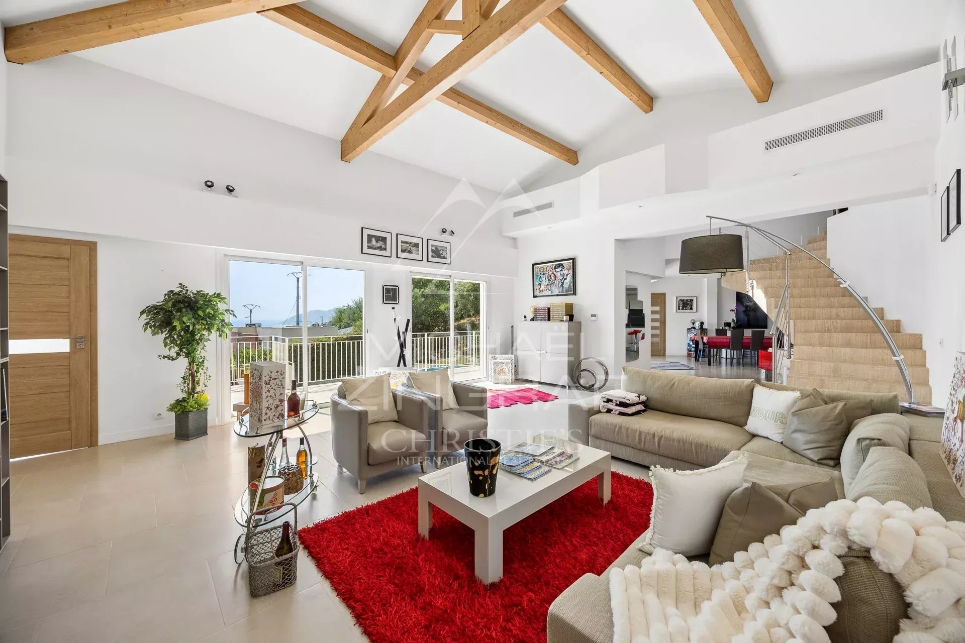 Salon d’une villa à Mandelieu-la-Napoule Intérieur d'une villa moderne avec un salon lumineux et un accès à l'extérieur, décoré avec un tapis rouge.