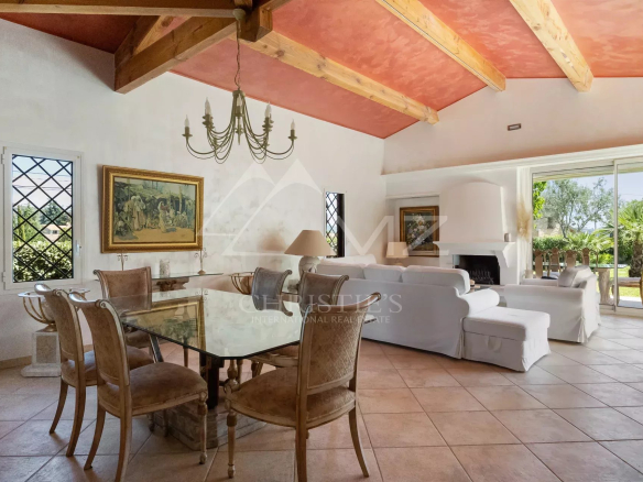 Intérieur d'une villa de plain-pied avec salle à manger et salon, fenêtres avec vue sur l'extérieur.