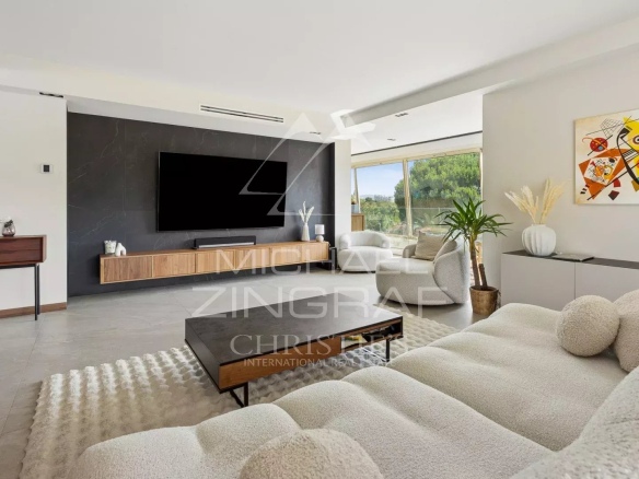 Intérieur d'un appartement moderne avec salon, télévision et accès à l'extérieur.