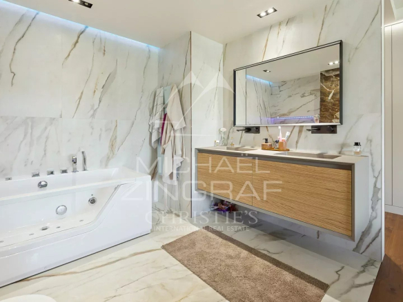 Salle de bain moderne avec baignoire et meuble en bois, murs en marbre.