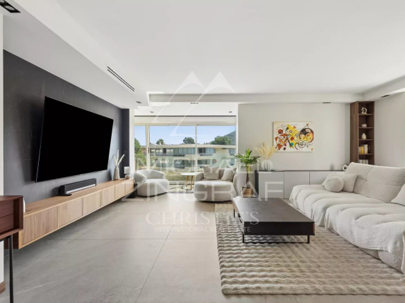 Salon spacieux d'un appartement moderne avec grandes fenêtres et décoration contemporaine.