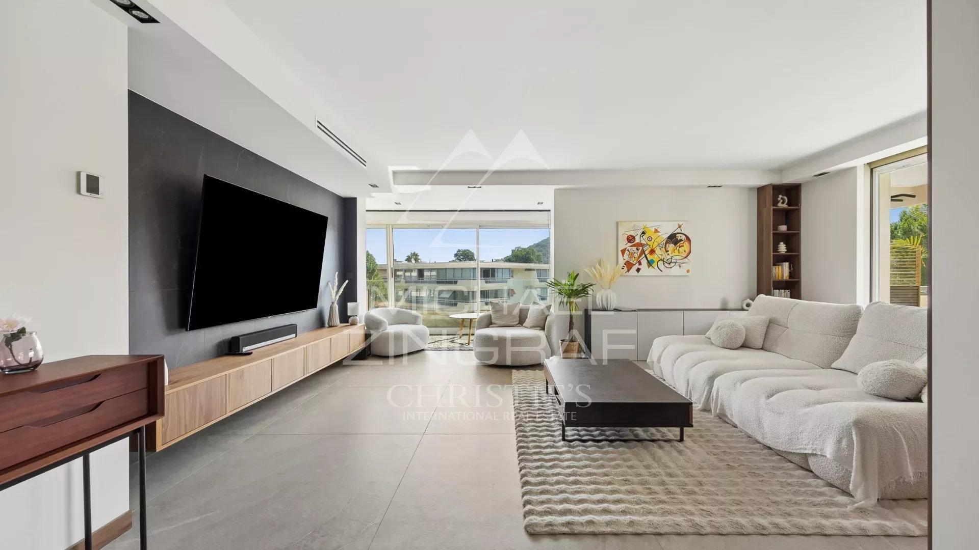Salon d’un appartement à Mandelieu-la-Napoule Salon spacieux d'un appartement moderne avec grandes fenêtres et décoration contemporaine.