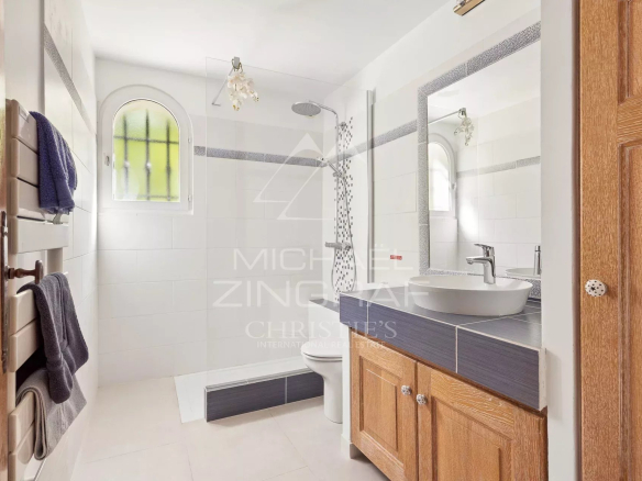 Salle de bain moderne avec douche, lavabo et meuble en bois.