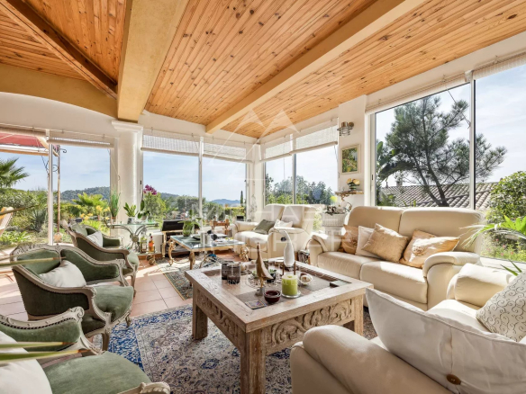 Interior of a Provençal villa with a bright living room and a view of the garden.