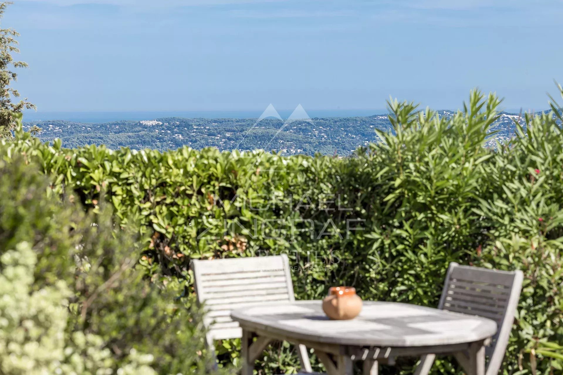 View from the terrace of a Provençal villa Sea view from a terrace with a wooden table and plants around it.