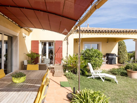 Terrace of a Provençal villa with garden furniture and view of the garden and swimming pool.