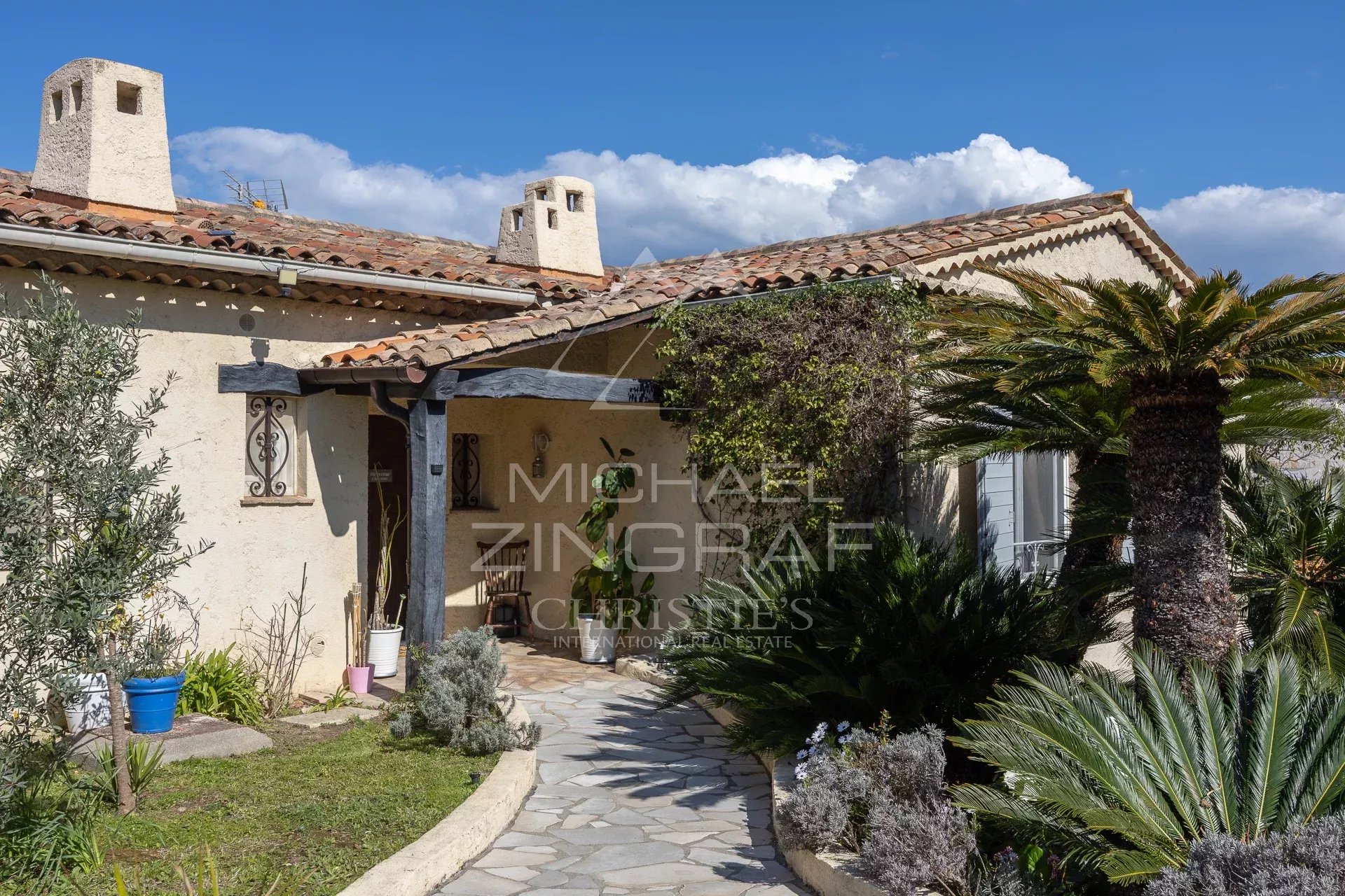 Entrance to an elegant family home in Mandelieu-La Napoule with garden and stone path.