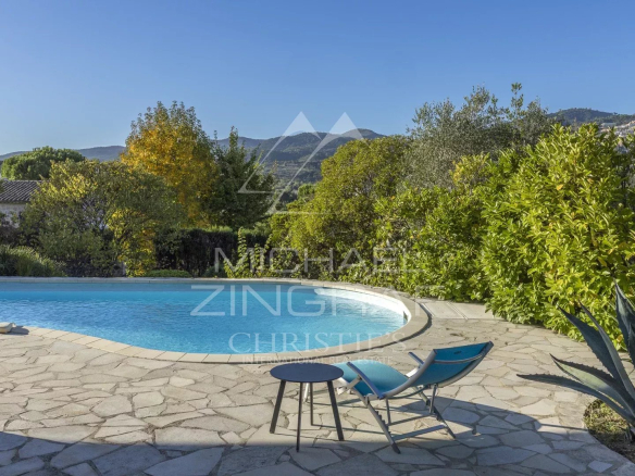 View of the pool and garden of a family home in Mandelieu-La Napoule with mountains in the background.
