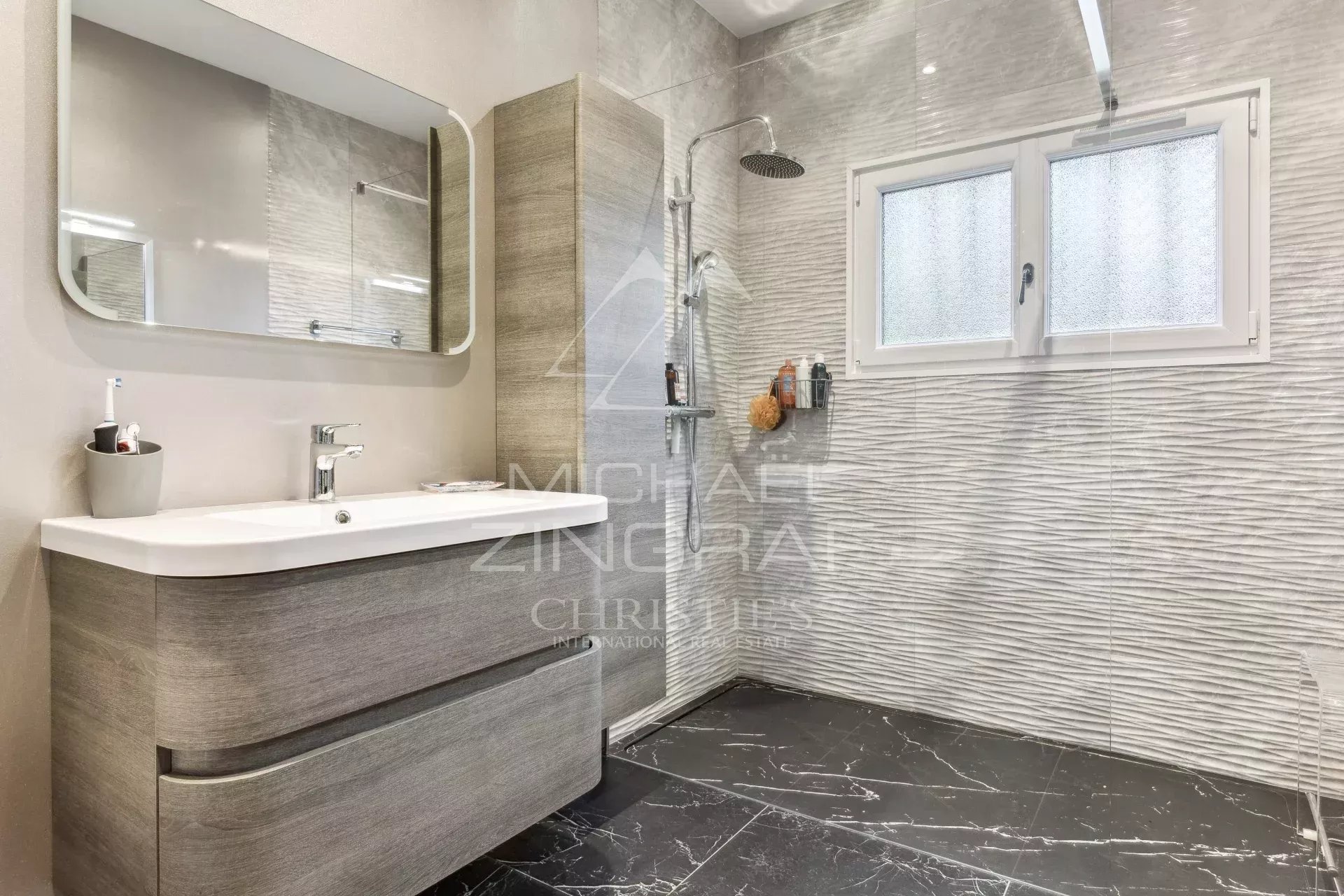 Modern bathroom with shower and wooden furniture, black and white tiles.