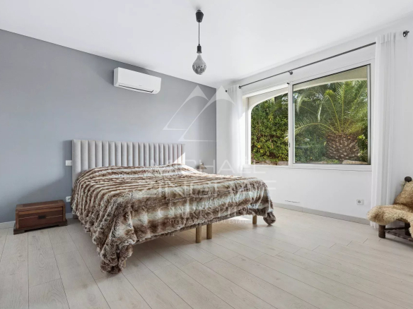 Chambre d'une propriété avec vue mer, décorée sobrement, fenêtres donnant sur la nature.