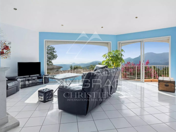 Intérieur d'une villa avec vue sur la mer, salon lumineux avec grandes fenêtres et mobilier moderne.