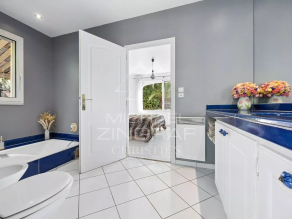 Salle de bains moderne avec baignoire et lavabo, carrelage blanc et murs gris.