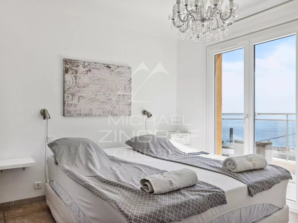 Chambre avec vue mer, lits jumeaux, décoration élégante et accès à un balcon.