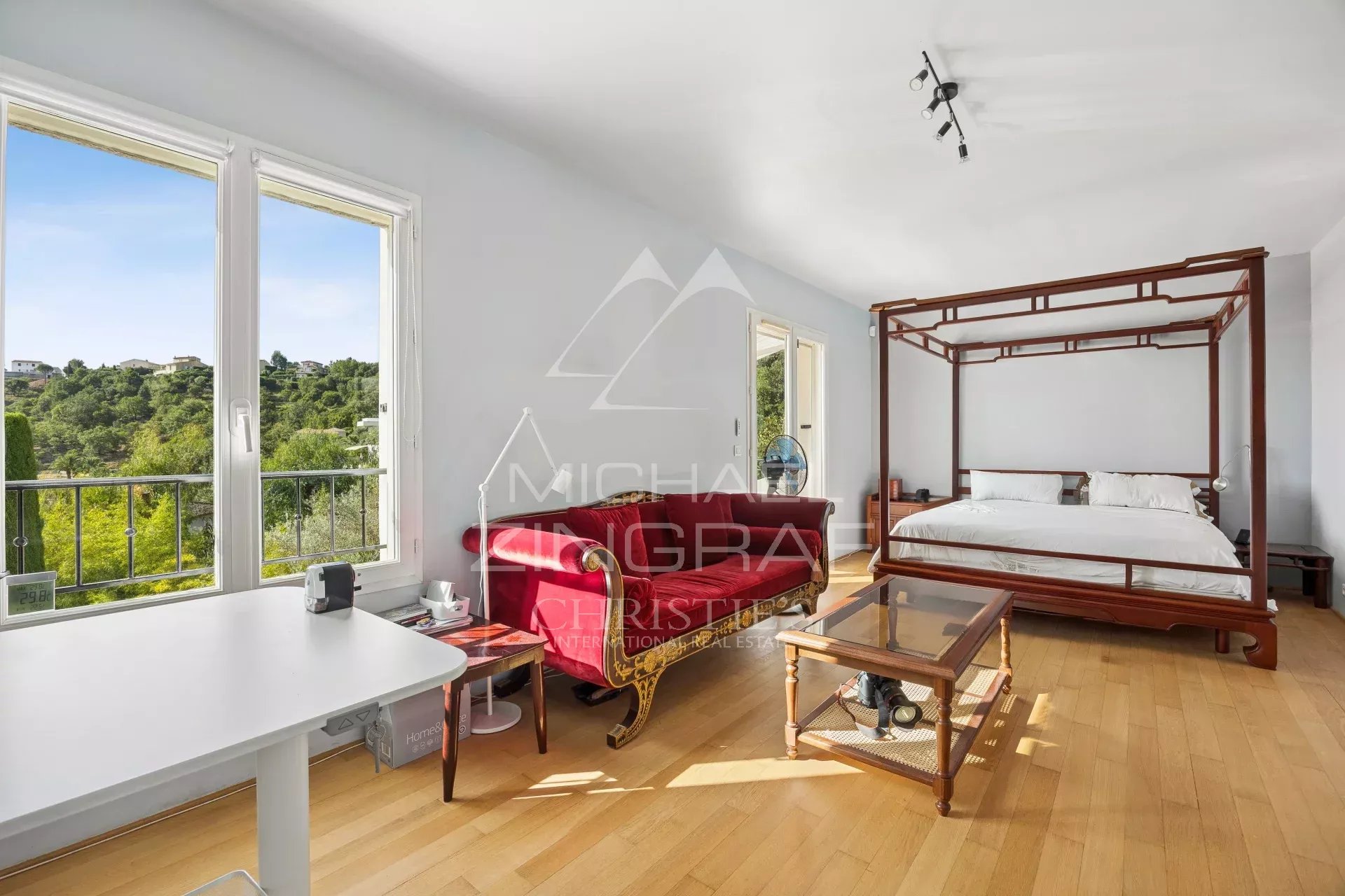 Chambre d'une propriété avec vue sur la nature, fenêtres ouvertes, mobilier moderne et traditionnel.