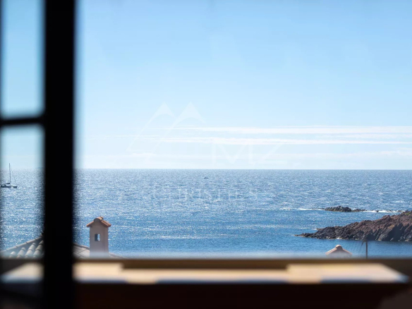 Vue sur la mer depuis une fenêtre, avec des roches et un ciel dégagé à Anthéor.