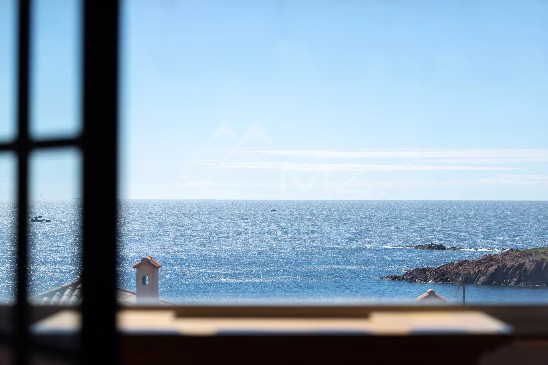 Vue mer à Anthéor Vue sur la mer depuis une fenêtre, avec des roches et un ciel dégagé à Anthéor.