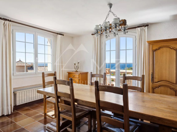 Salle à manger avec vue sur la mer, fenêtres ouvertes, mobilier en bois, à Anthéor.