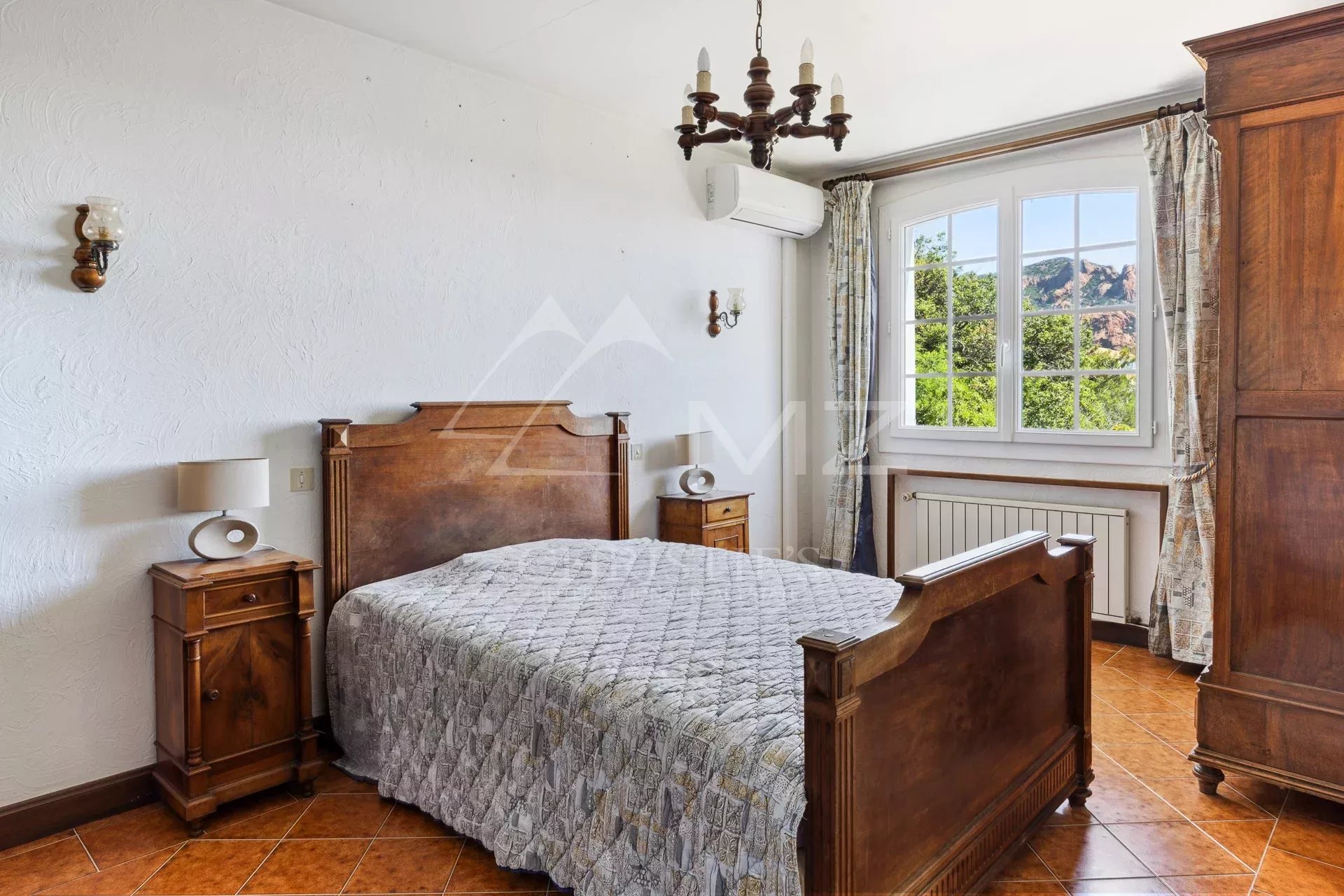 Chambre à Anthéor Chambre avec lit en bois et fenêtre donnant sur la végétation et les roches rouges d'Anthéor.