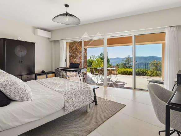 Chambre d'une villa avec vue sur la mer et les collines, accès à une terrasse.